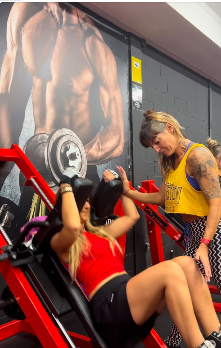 Eva Gómez Ruiz de EVAFIT entrenando a una clienta en un ejercicio de prensa en el gimnasio Pro Strength Irún. Entrenamiento de fuerza con enfoque en técnica y progresión