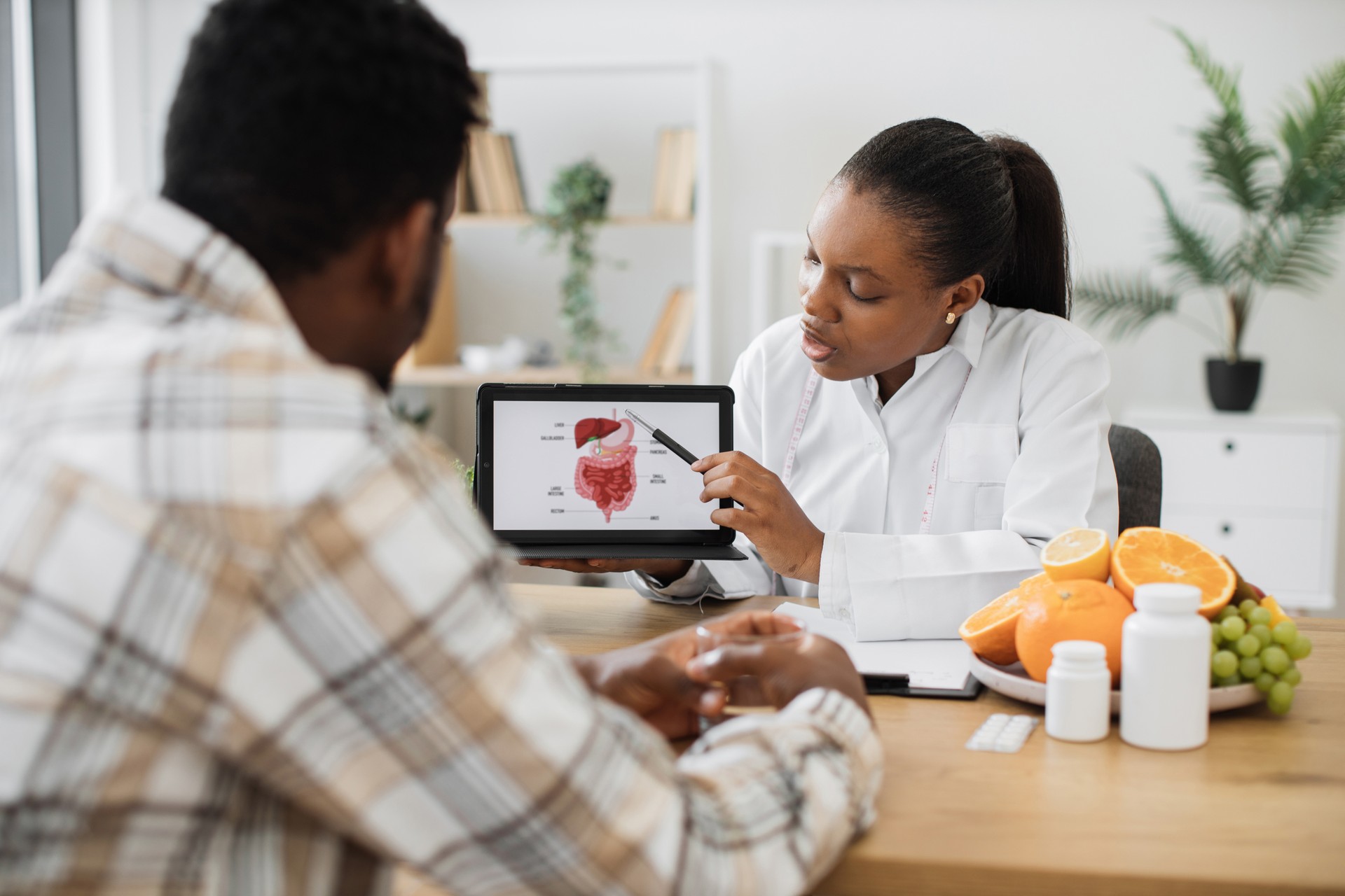 Mujer sosteniendo una tableta con tracto gastrointestinal mientras asesora al cliente